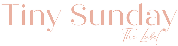 Logo of 'Tiny Sunday The Label' with a pinkish hue on a white background